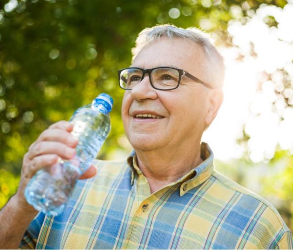 older man drinking from a water bottle outdoors