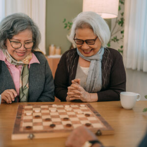 Happy senior friends play chess at a senior center.